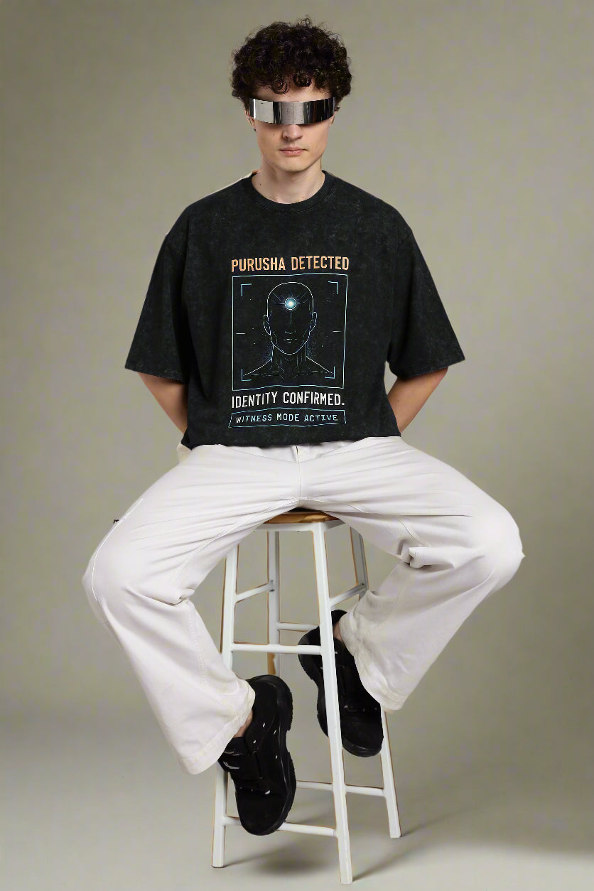 Oversized acid wash black T-shirt with “Purusha Detected” text. Inspired by Vedic philosophy, in dark grey charcoal tones for a bold, streetwear look.