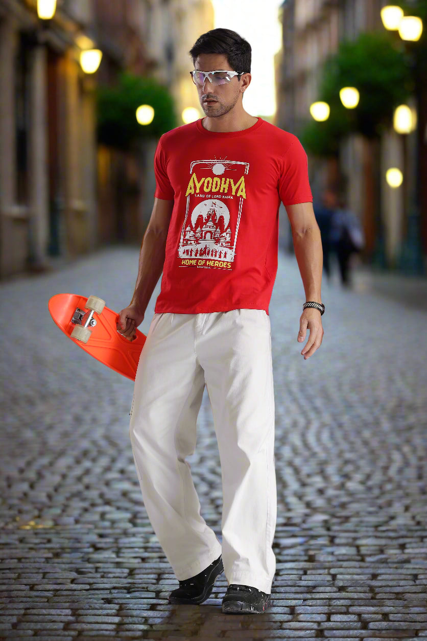Ayodhya themed red graphic T-shirt featuring Ramayana-inspired temple artwork and 'Home of Heroes' text, worn by a male model on a cobblestone street – EpicThreadsIndia spiritual streetwear