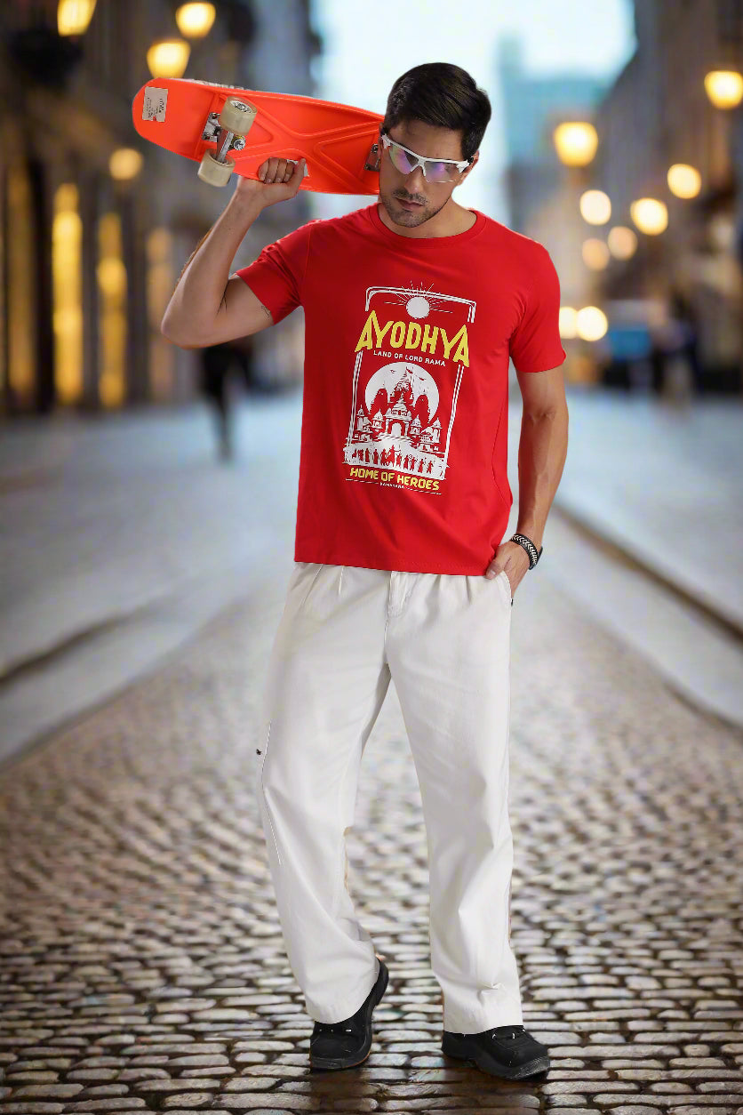 Ayodhya themed red graphic T-shirt featuring Ramayana-inspired temple artwork and 'Home of Heroes' text, worn by a male model on a cobblestone street – EpicThreadsIndia spiritual streetwear